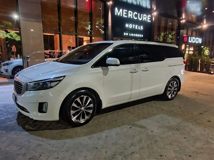 Minivan Kia Carnival branca diante da entrada de um hotel em Belo Horizonte, à noite