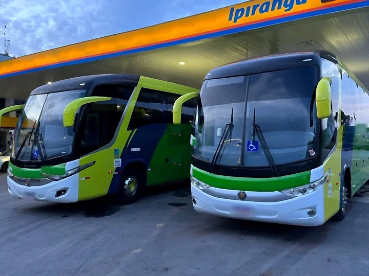 Dois ônibus rodoviários Marcopolo Paradiso lado a lado em posto de combustível, ao entardecer