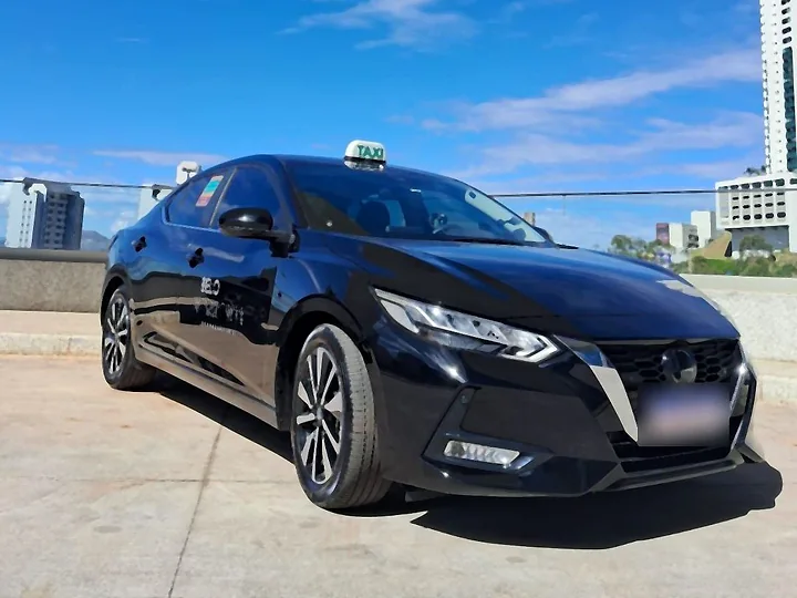 Táxi executivo Nissan Sentra preto estacionado em área aberta de Belo Horizonte, sob céu azul