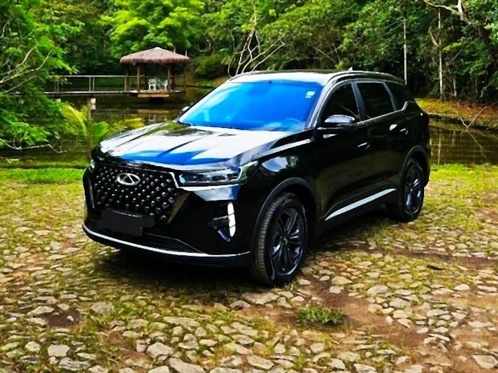 SUV executivo Caoa Chery Tiggo 7 preto em pátio de pedra cercado de mata