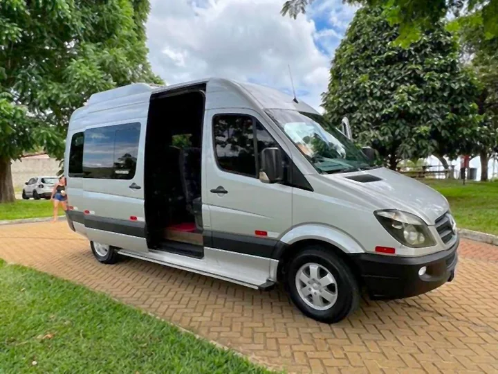 Van executiva Sprinter prata com a porta lateral aberta em um parque arborizado