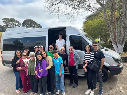 Grupo de clientes reunido em frente à van executiva com motorista antes de um passeio