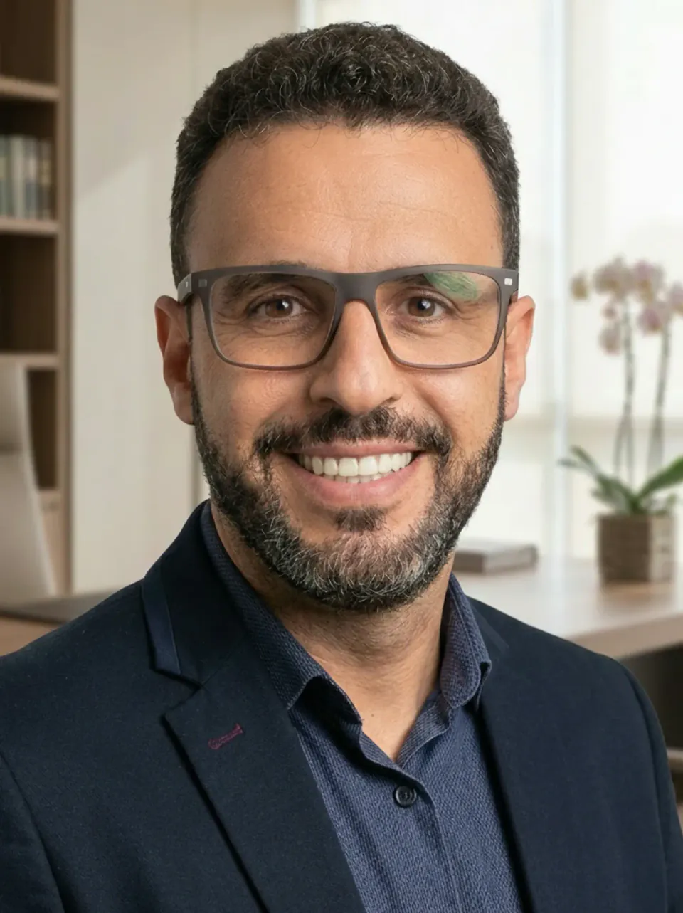 Gustavo Souza, fundador da TEVO – Transporte Evolutivo, de óculos e blazer azul-marinho, sorrindo em um escritório