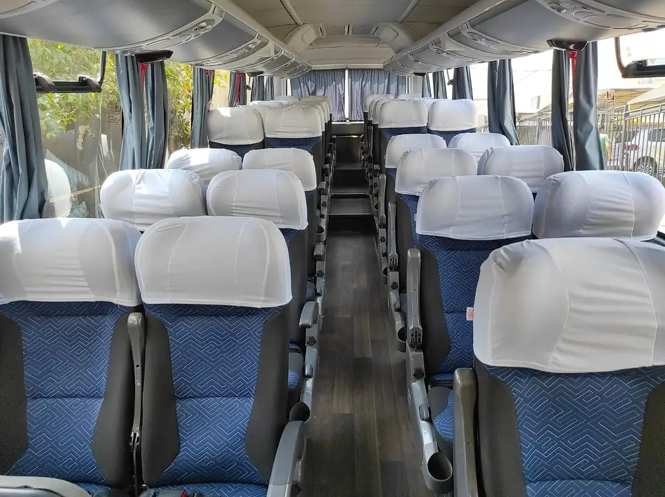 Poltronas azuis com capas brancas no interior de um ônibus rodoviário