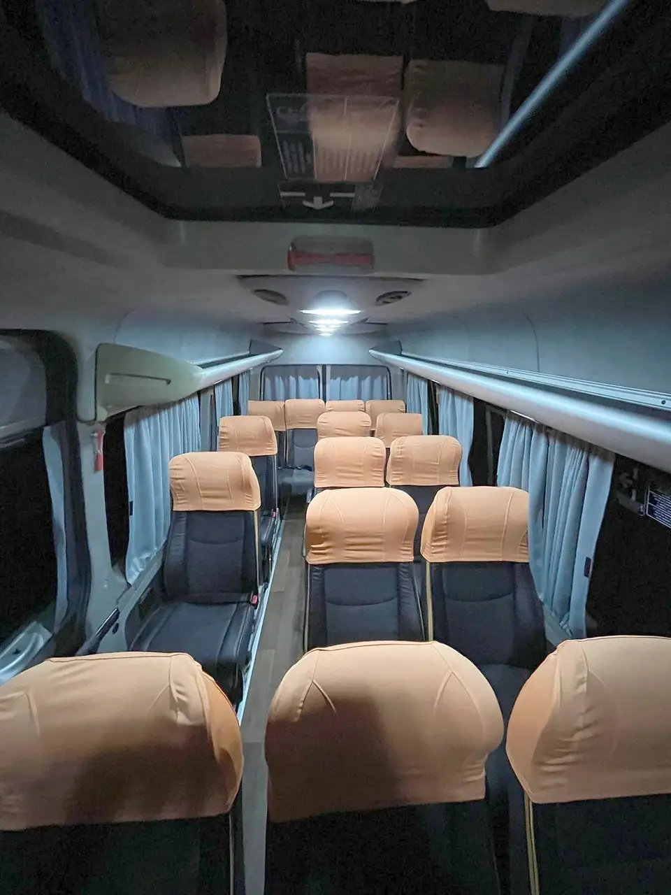 Interior de van com poltronas de capas caramelo e iluminação no teto