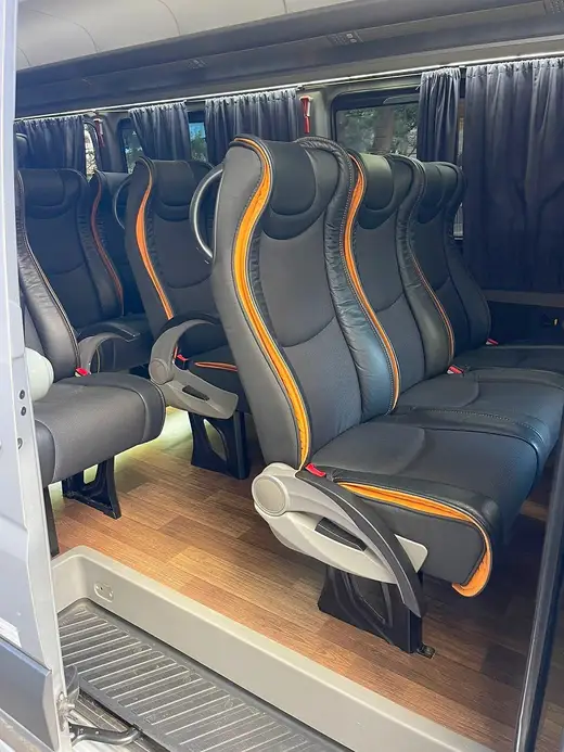 Poltronas reclináveis pretas com detalhes laranja e cortinas em uma van executiva