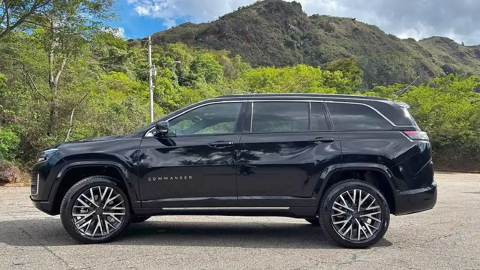 Jeep Commander preto de perfil em uma estrada, com a serra mineira ao fundo