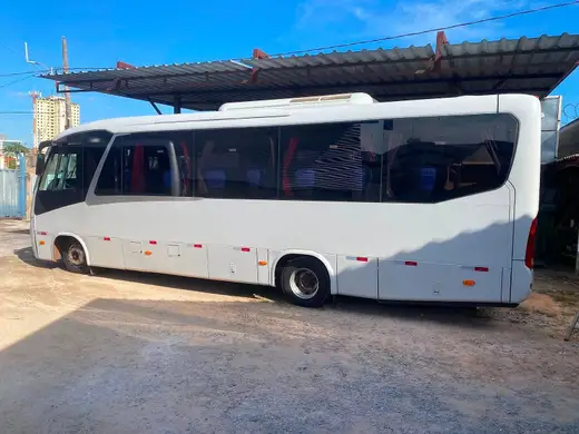 Micro-ônibus branco com janelas panorâmicas estacionado em pátio