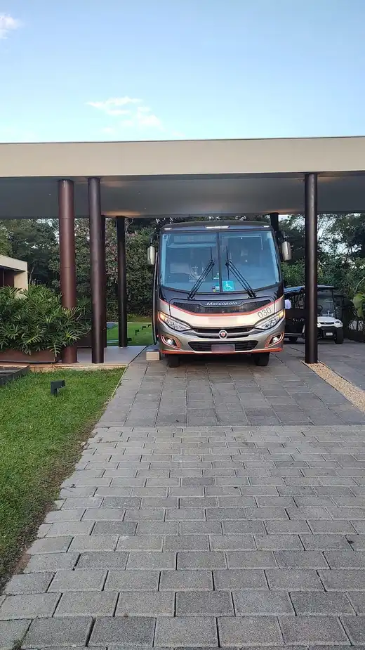 Micro-ônibus Marcopolo visto de frente, estacionado sob a cobertura de um edifício moderno