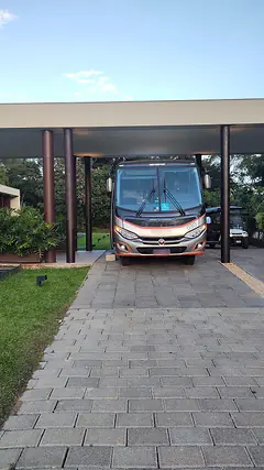 Micro-ônibus Marcopolo visto de frente, estacionado sob a cobertura de um edifício moderno