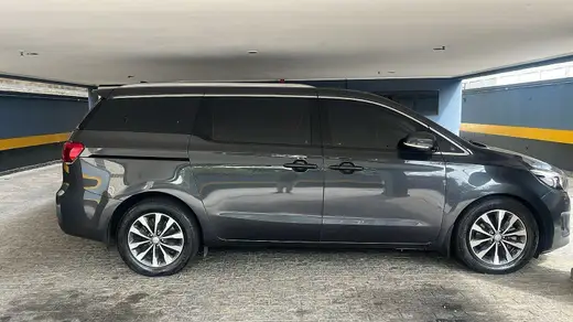 Minivan Kia Carnival cinza vista de perfil em garagem coberta