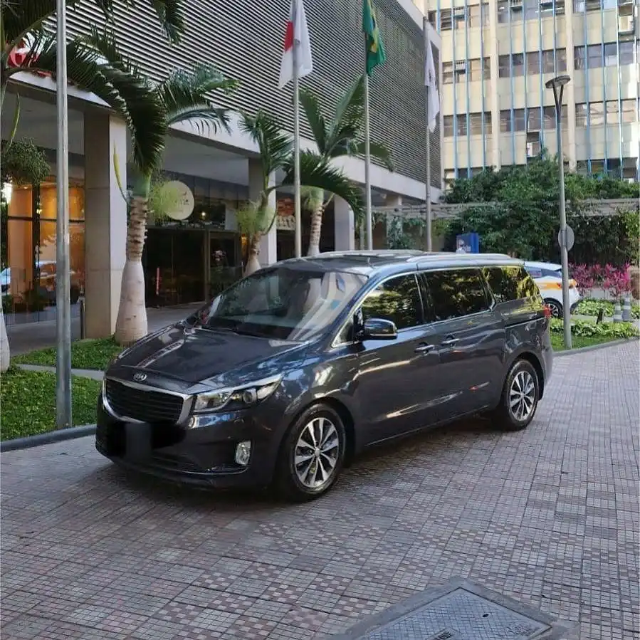 Minivan executiva escura na entrada de um hotel com bandeiras