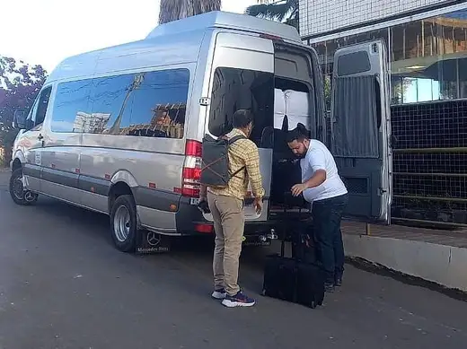 Motorista acomodando as malas do passageiro na van executiva para o transfer ao aeroporto