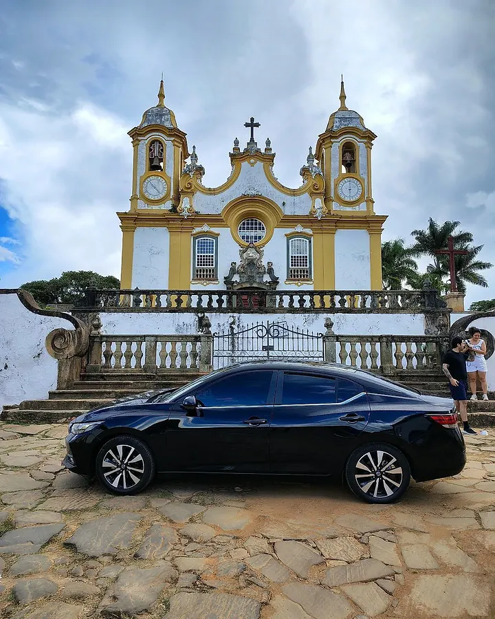 Táxi executivo preto de perfil diante da Matriz de Santo Antônio, em Tiradentes