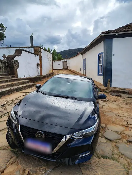 Sedan executivo preto em rua de pedra entre casarios coloniais