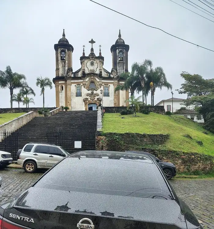 Sedan executivo preto diante de uma igreja barroca no alto de uma escadaria, em Ouro Preto