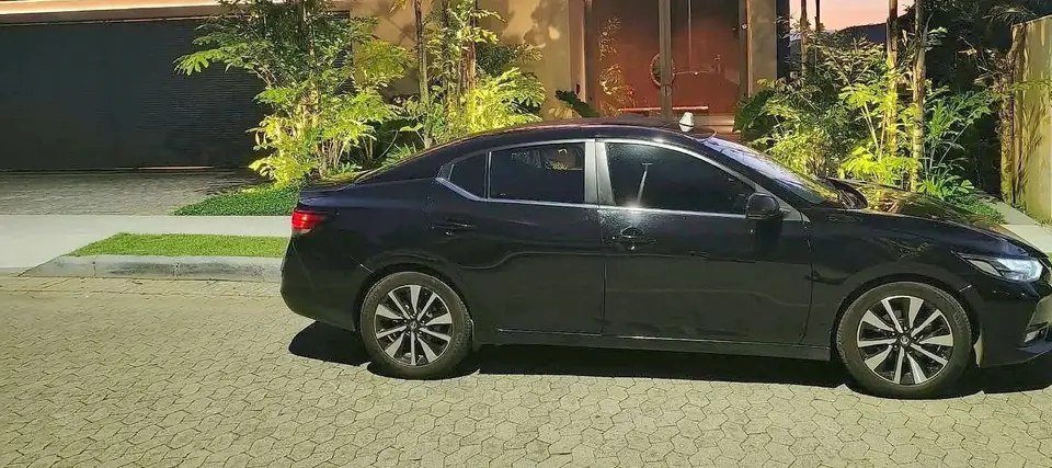 Táxi executivo preto estacionado ao anoitecer, pronto para buscar o passageiro