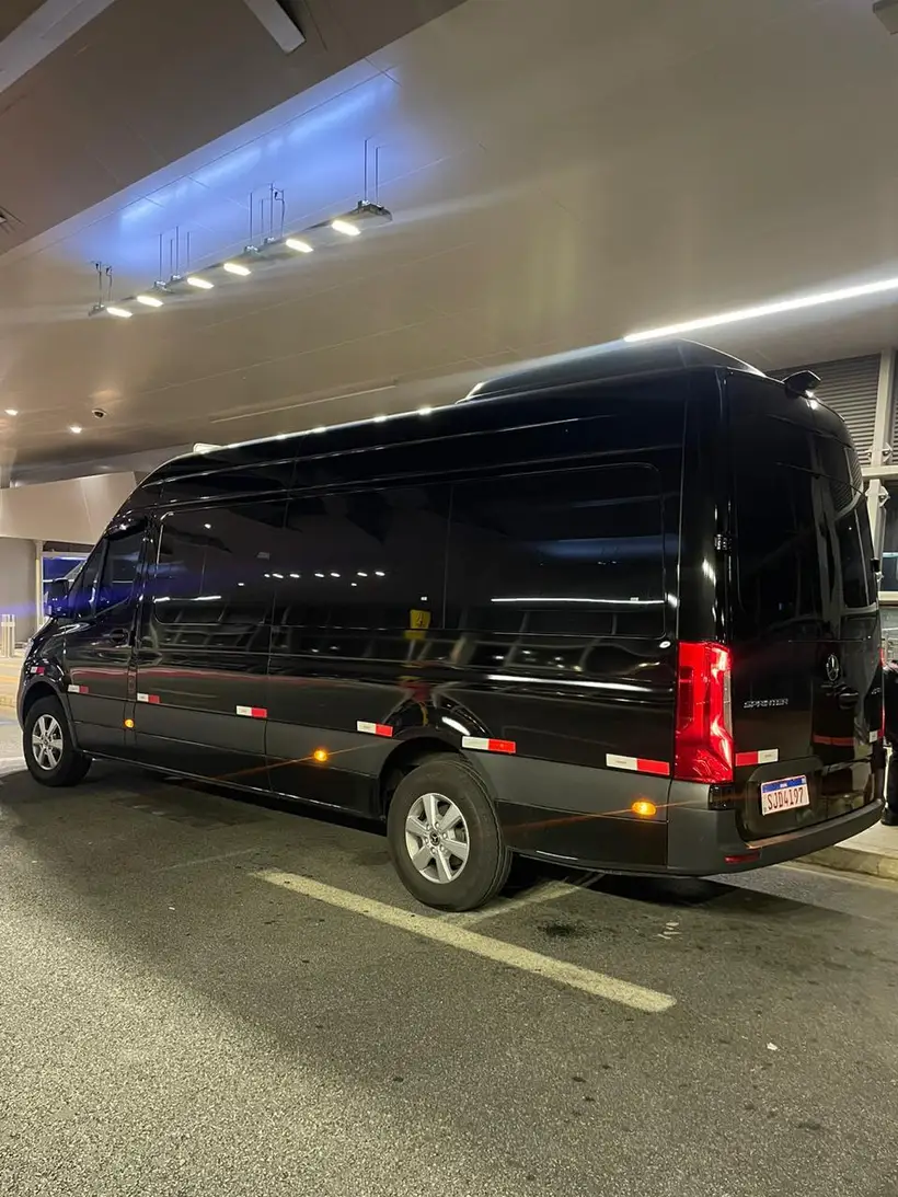 Van executiva preta em estacionamento coberto, de noite