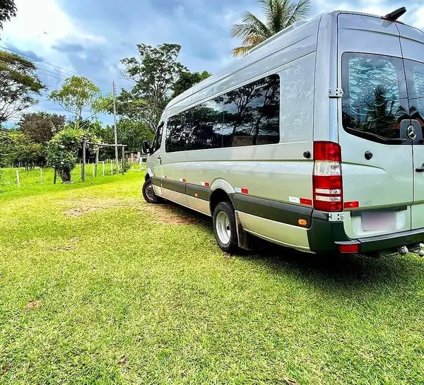 Van executiva Sprinter prata em um gramado, sob céu com nuvens